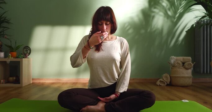 Woman Practicing Breathing Meditation Exercise Indoors Slow Motion, Female Sitting Cross Legged On Yoga Mat In Calm Wellness Studio, Concept Of Mindfulness And Relaxation
