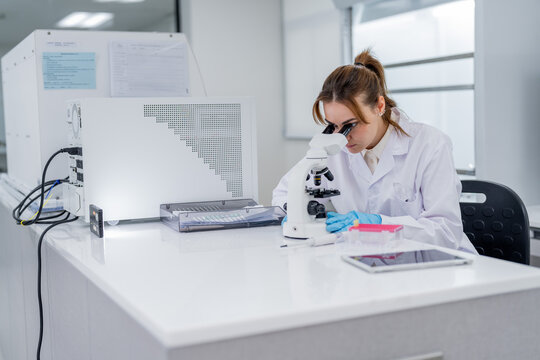 Scientist works with microscope in laboratory setting during daytime in modern facility