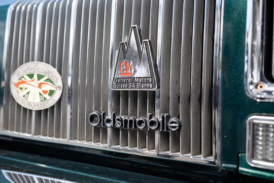 Zurich, Switzerland, April 19, 2026. A close up shot of an Oldsmobile grille with a General Motors Suisse SA Bienne badge at Albisguetli Classics.