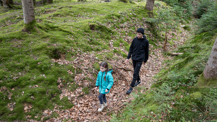 Obraz premium Exploring a lush green forest trail with a child and guardian during a serene autumn day filled with nature's beauty and vibrant colors