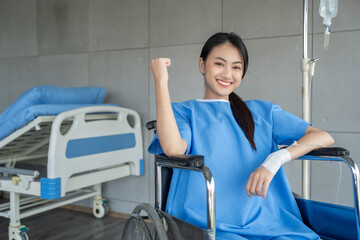 Obraz premium A cancer patient sits in a wheelchair with an IV drip looking stressed and sad. Asian Woman receiving IV therapy in a wheelchair showing visible signs of stress and depression