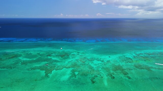 Drone pulls back to reveal Seven Mile Beach, turquoise reef water, and shoreline in Grand Cayman
