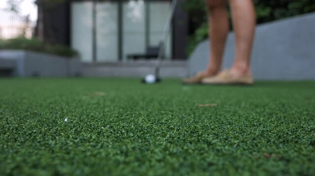 Close-up of a golf ball and putter on artificial turf
