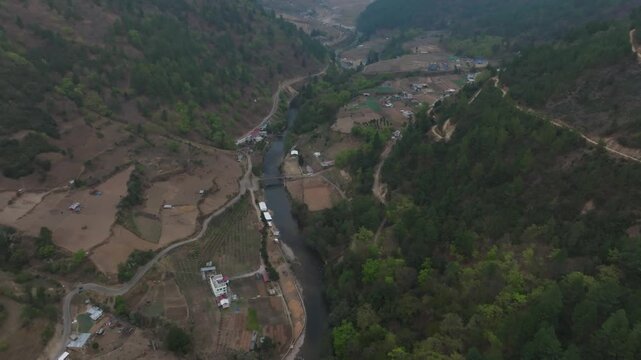 Dirang Valley in Arunachal Pradesh shows terraced fields and scattered settlements along a Dirang Chu river winding through forested mountain slopes. Aerial shows the valley's agricultural layout.