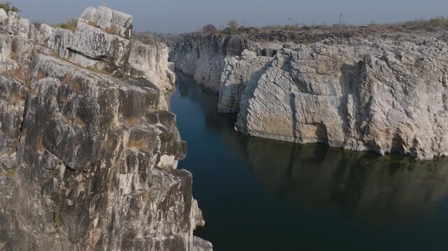 Bhedaghat's Narmada River flows between towering white marble cliffs and Swarg Dwari in Jabalpur District. Aerial perspective reveals the dramatic narrow gorge carved through layered rock formations.
