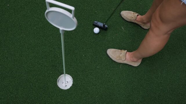 Close-up of a golf ball and putter on artificial turf