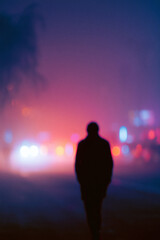 Obraz premium Solitary Figure Walking Through Neon City Street at Night with Cinematic Emotional Tone and Soft Lighting