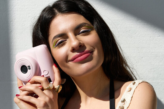 Portrait of a beautiful young woman with natural summer makeup and a playful pink camera