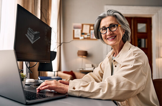 Smiling senior woman working on laptop in home office.