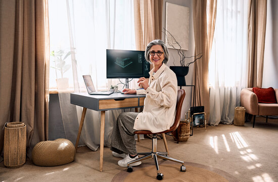 Smiling senior woman working in bright home office.