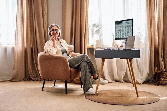 Senior woman working from home with coffee in cozy home office.