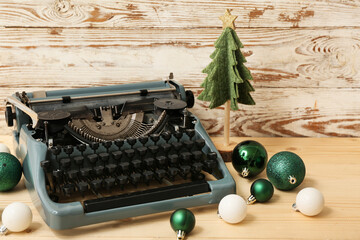 Naklejka premium Vintage typewriter with Christmas tree and balls on wooden background