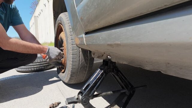 Man removing a flat tire from a car for replacement