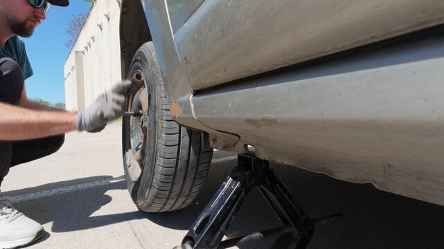 Man screwing bolts to install a spare wheel on a car