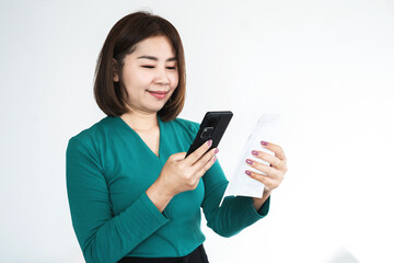 Fototapeta premium smiling Asian woman in a green shirt uses a smartphone to scan a QR code on a paper receipt for a mobile payment. Concept of digital banking, e-wallet, contactless technology, and modern lifestyle