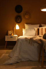 Interior of bedroom with glowing lamp on table at night © Pixel-Shot