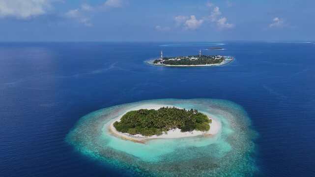 Aerial view of lush tropical islands surrounded by turquoise coral reefs and deep blue ocean water under a clear sky Kendhoo, Baa Atoll, Maldives.