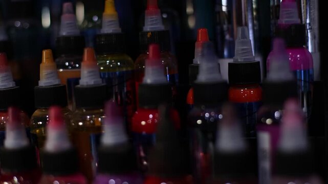 Palette of multicolour tattoo inks in small bottles. Selective focus, blurred.