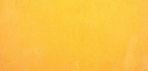 Fototapeta premium Full frame texture of a vibrant mustard yellow painted wall with a subtle grainy plaster finish for a minimalist background.