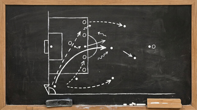 Coach drawing soccer strategy on chalkboard