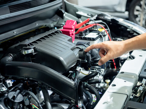 Professional mechanic points toward the air intake system of a clean modern internal combustion engine