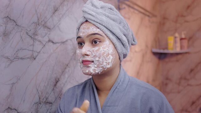 Indian woman applying organic face mask during her skincare routine in bathroom.