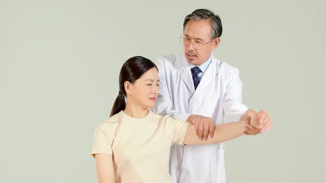 Orthopedic specialist doctor in a white lab coat giving young woman patient physiotherapy with hand lift, doing stretching patient's arm and examined her elbow at physical therapy checkup treatment