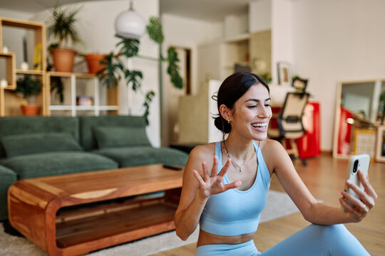 Portrait of a fit latina  girl young woman exercising practicing yoga or fitness and talking on mobile phone having a call  at home