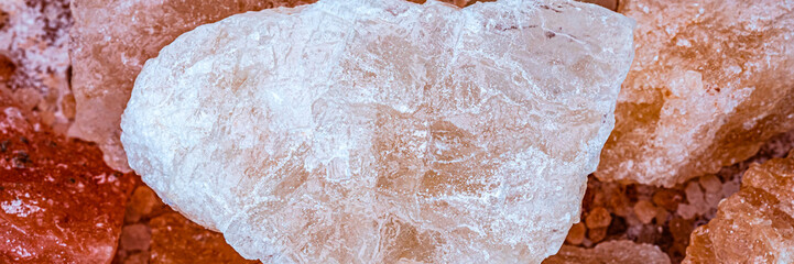 Fototapeta premium Large crystal salt rock placed on a pile of smaller salt rocks in a natural setting during daylight