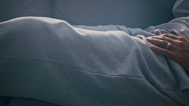 Pan shot of Biracial woman lying on couch in apartment wearing ankle bracelet, staring at ceiling while feeling sad and isolated