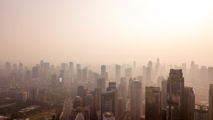 Fototapeta premium Dense Smog and Air Pollution Enveloping Modern City Skyscrapers at Golden Hour