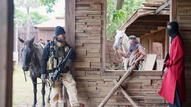 Group of men with soldier and arab clothes stand with holding gun and discuss together also stay in building.