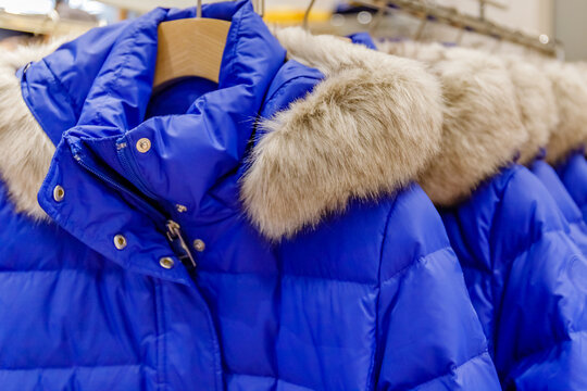 Bright blue winter coat with fur trim displayed in a clothing store at a shopping mall during the winter season