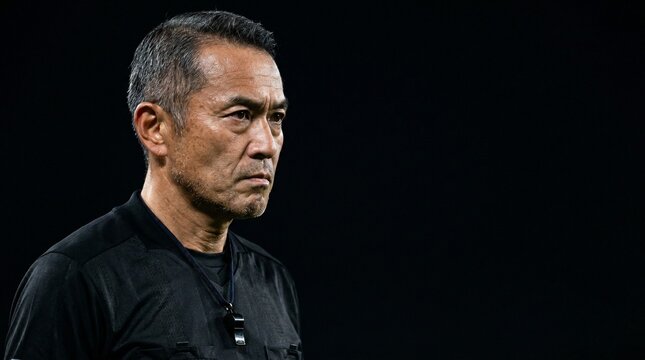 漆黒の静寂とプロの眼差し。公平な判断を下す日本人男性審判の緊張感のあるクローズアップ