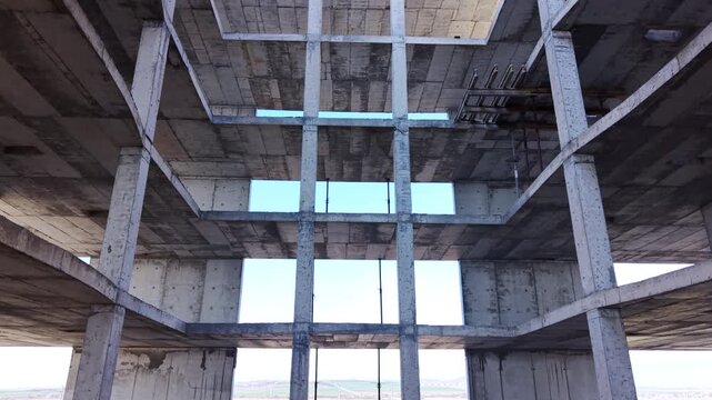 Low angle view of internal rectangular opening within multi story reinforced concrete structure. Looking up through central void of concrete building frame. Aerial.