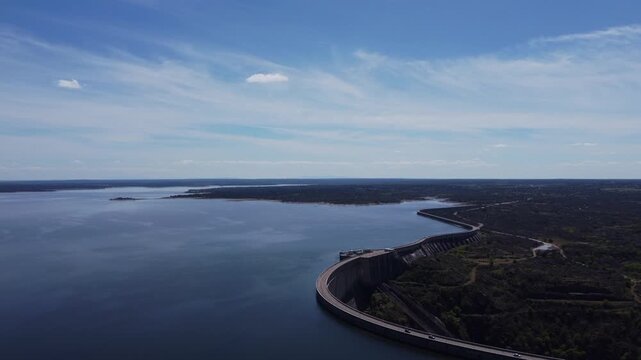 4K aerial panoramic view of the Almendra Reservoir in Salamanca, Spain. High drone flight over the massive concrete dam wall and vast water under a sunny sky with views of the plateau
