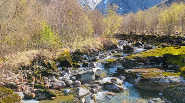Slow Upward Pan from Crystal Clear Mountain Stream to Dramatic Briksdal Glacier and Snow-Capped Peaks Norway