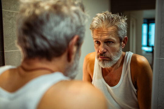 Mature man looking at bathroom mirror at home