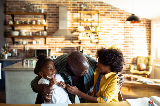 Grandfather hugging two children at kitchen table