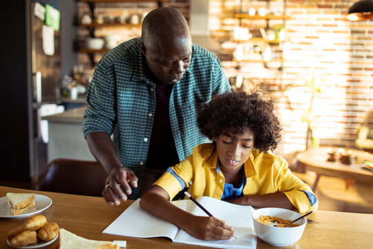 Grandfather helping child with homework at kitchen table