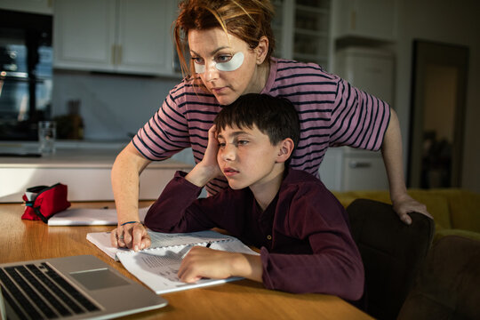 Mother helping son with homework at kitchen table