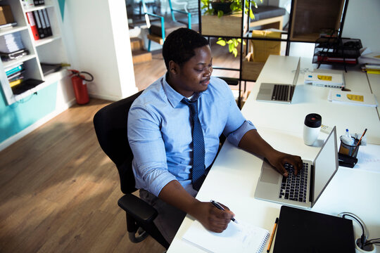 Businessman working at laptop and taking notes in modern office