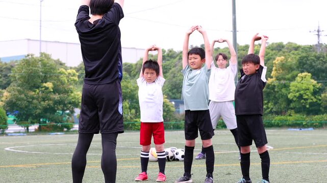 少年サッカーチームとコーチのウォーミングアップ風景