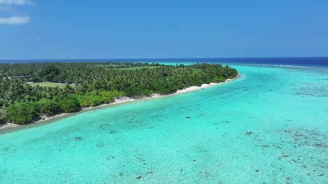 Aerial view of the tropical island of Thoddoo featuring a turquoise lagoon, coral reefs, and dense palm tree forests under a clear blue sky Thoddoo, Alif Alif Atoll, Maldives.