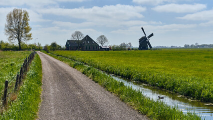 Dutch Countryside Landscape With Traditional Windmill Farmhouse And Canal In Spanbroek Netherlands © VeugerStock
