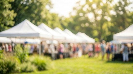 Fototapeta premium A sunny outdoor fair featuring white tents on a green lawn.