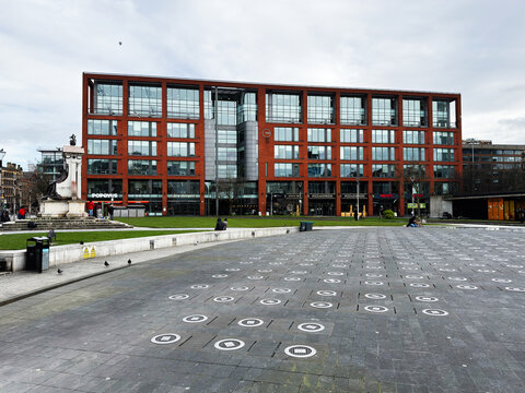 Modern office building and public plaza with people relaxing in Manchester, UK city center