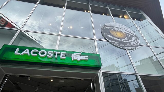 Lacoste flagship store exterior featuring iconic green logo and creative crocodile eye decorative glass decal on Harajuku street boutique - Tokyo, Japan, January 17, 2024