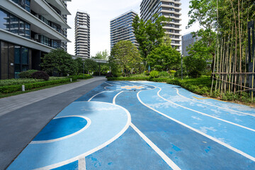 Blue rubber running track in modern residential community surrounded by high-rise buildings and greenery © zhu difeng