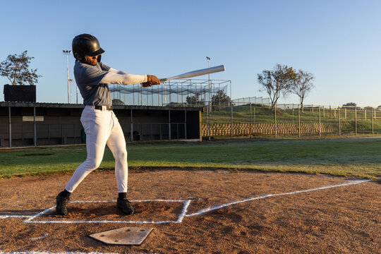 Vertical video: Swinging batter wearing helmet, following pitch arriving at home plate, holding bat